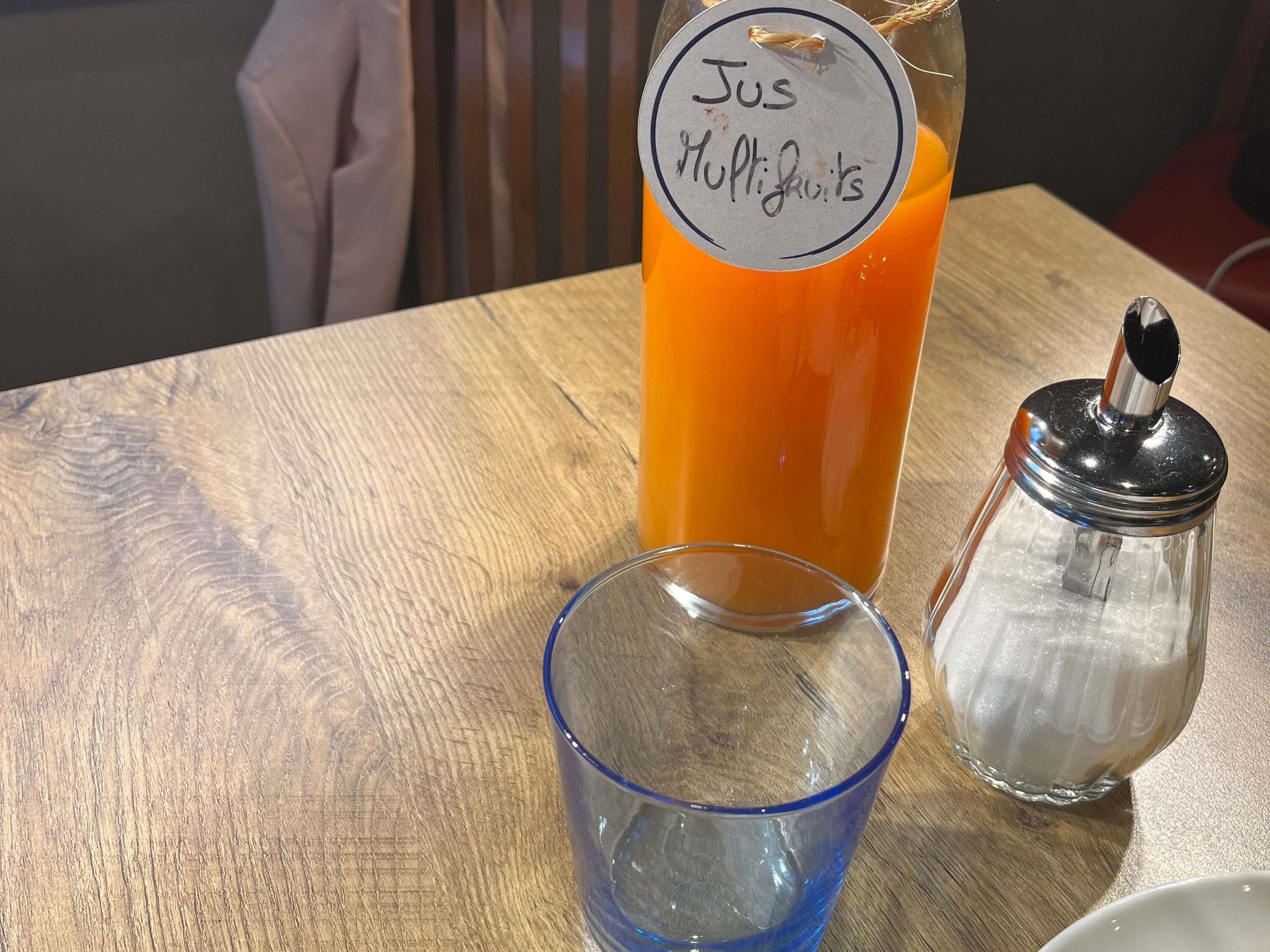 Ett träbord med en glasflaska märkt med texten ”Jus Hultigrafts” och ett genomskinligt glas.