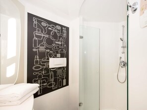 Une salle de bain avec une douche, des toilettes et une serviette.