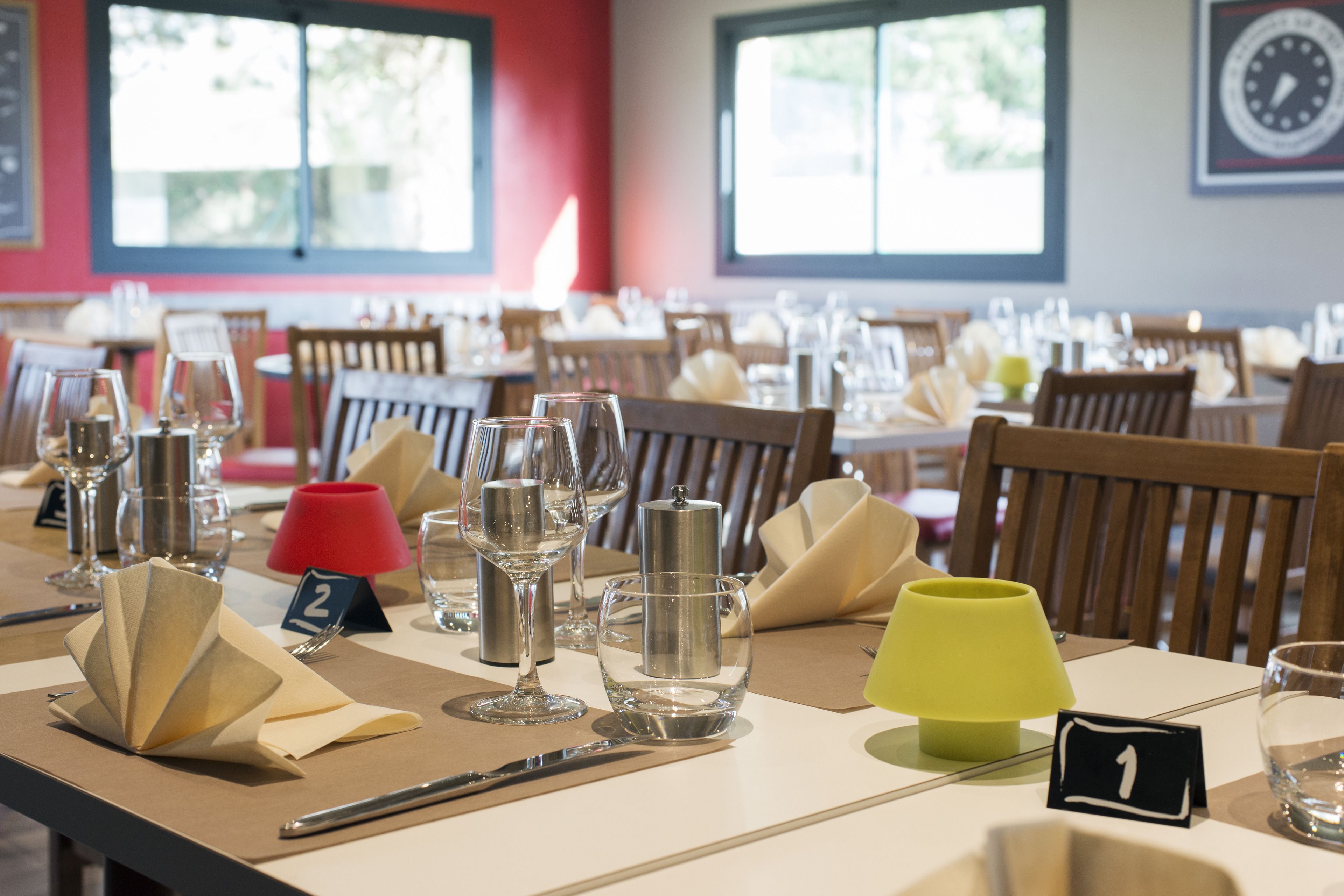 A dining table set with numbered place cards, wine glasses, and a yellow table lamp.