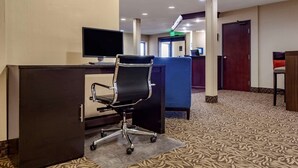 A hotel lobby with a reception desk, a computer, a black office chair, a blue seating area, and a patterned carpet. - Comfort Inn Grand Island North (Grand Island)