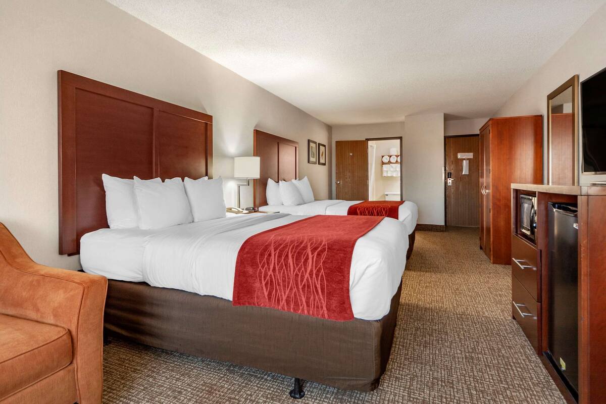 A hotel room with a large bed, a desk, a chair, and a TV.
