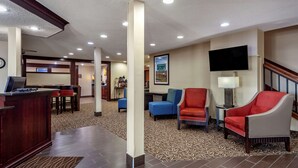 A hotel lobby with a reception desk, seating area, and a staircase. - Comfort Inn Grand Island North (Grand Island)