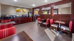 A hotel lobby with a kitchen area, seating with red and beige chairs, and a buffet setup. - Comfort Inn Grand Island North (Grand Island)
