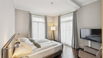A hotel room with a bed, a TV, a chair, and a lamp.