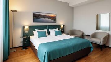 Une chambre d’hôtel avec un grand lit, deux tables de chevet, une chaise, une petite table ronde, un lampadaire et un téléviseur fixé au mur.