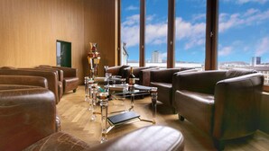 A modern lounge with leather sofas, a glass coffee table, and a view of the cityscape through large windows. - GLANDON Rooms Elite (Biel)