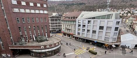 Un edificio de varios pisos con una entrada circular, un restaurante llamado 'BRASSER RESTAURANT' y un edificio moderno con techo inclinado.