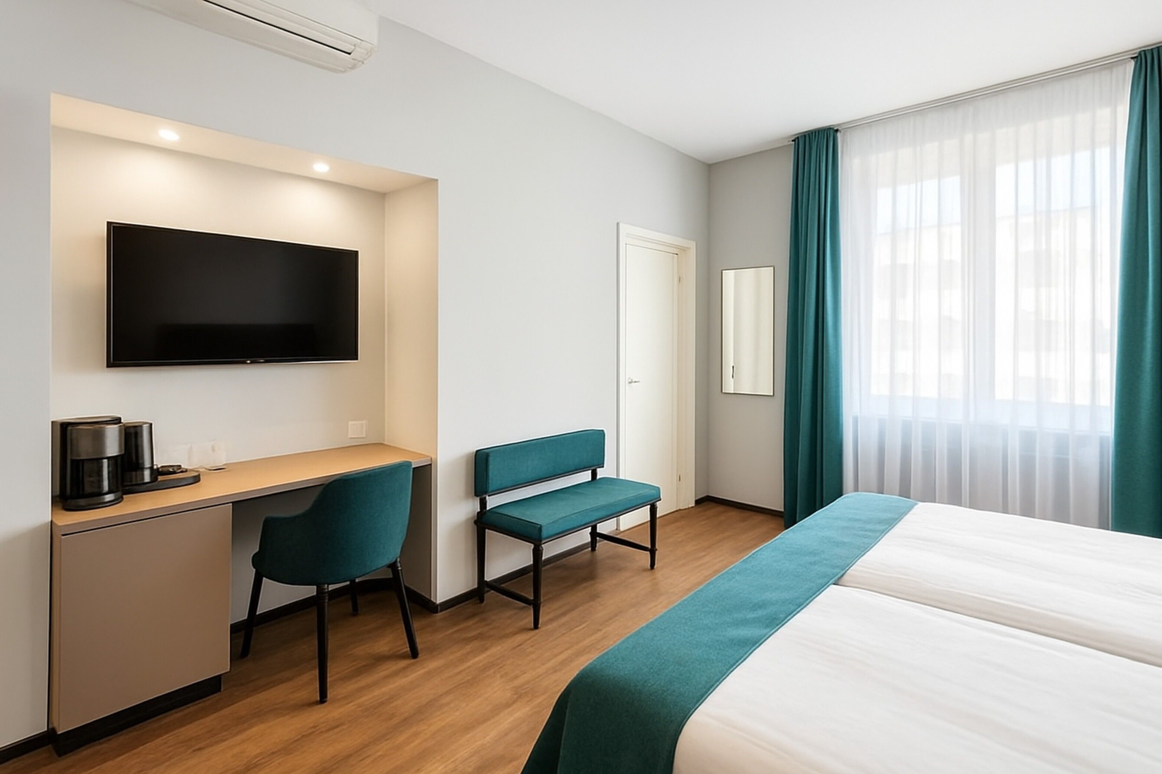 Quarto de hotel com cama, escrivaninha com cadeira, televisão e janela com cortinas.