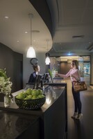 A reception area with a reception desk, a clock, and a plant.
