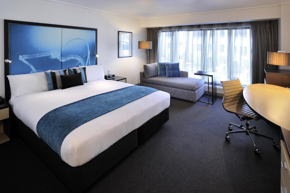 Una habitación de hotel moderna con una cama grande, un sofá, un escritorio y una silla.