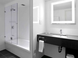 A modern bathroom with a glass-enclosed shower, a black sink vanity, and a large mirror above the sink.
