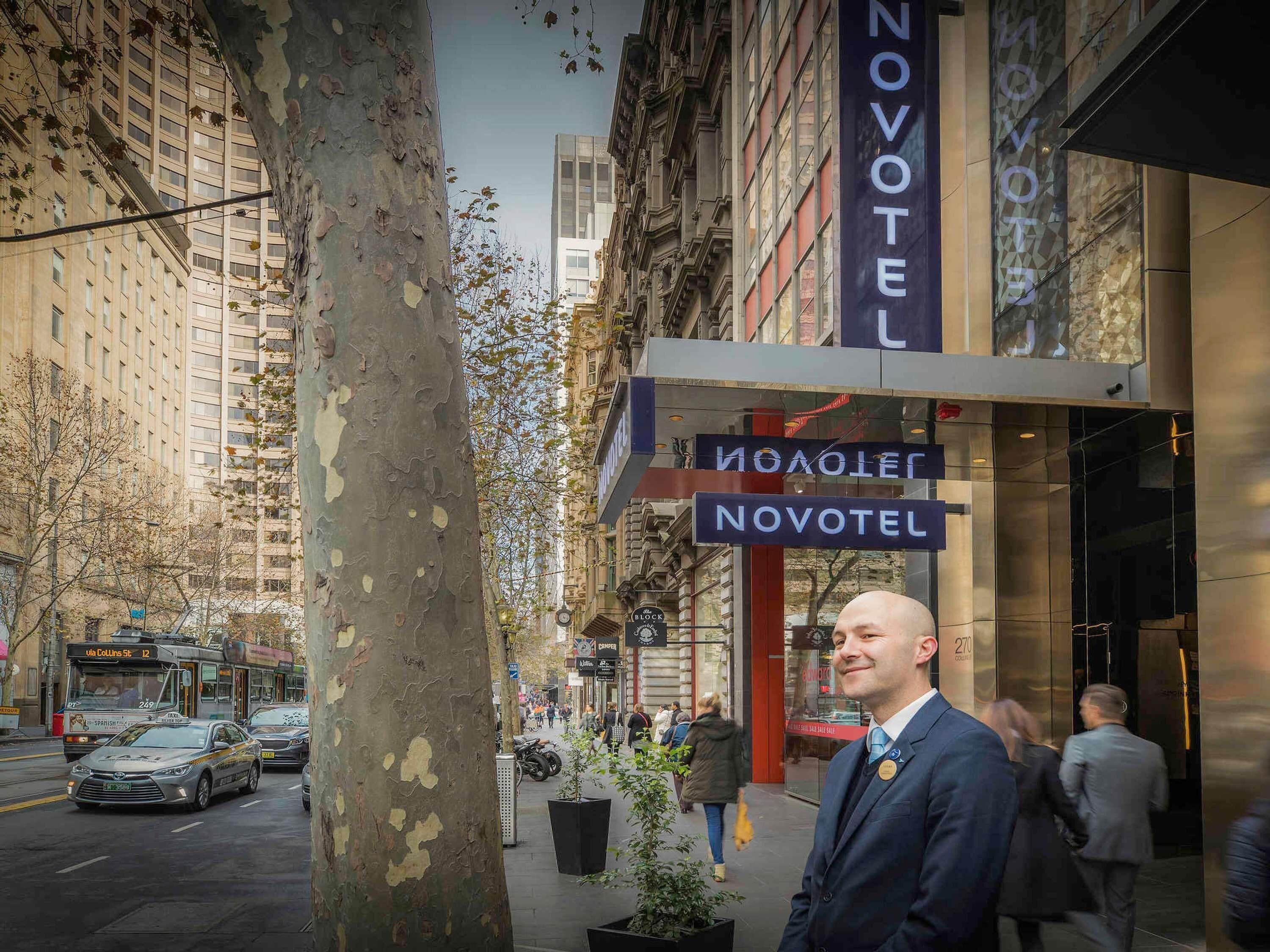 A man standing in front of a Novotel hotel with a signboard.