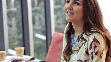 A person seated at a table with a window view.
