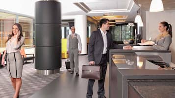 A modern hotel lobby with a reception desk, a large pillar, and a check-in counter.