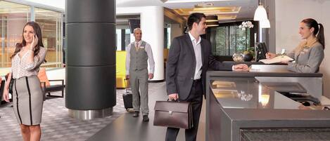 Un moderno vestíbulo de hotel con mostrador de recepción, un pilar grande y una mesa de registro.