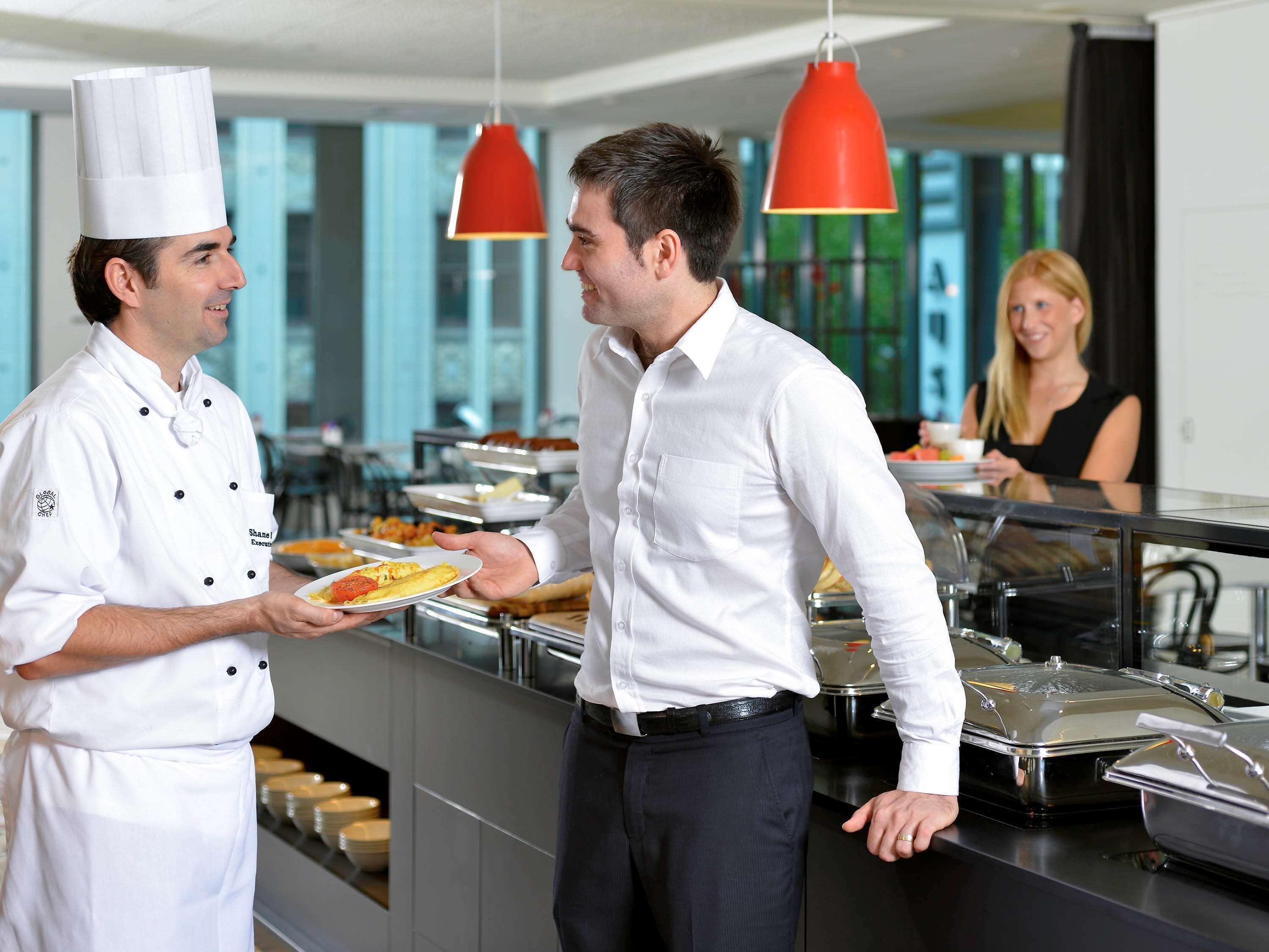 A buffet setup with multiple food stations and a person serving food.