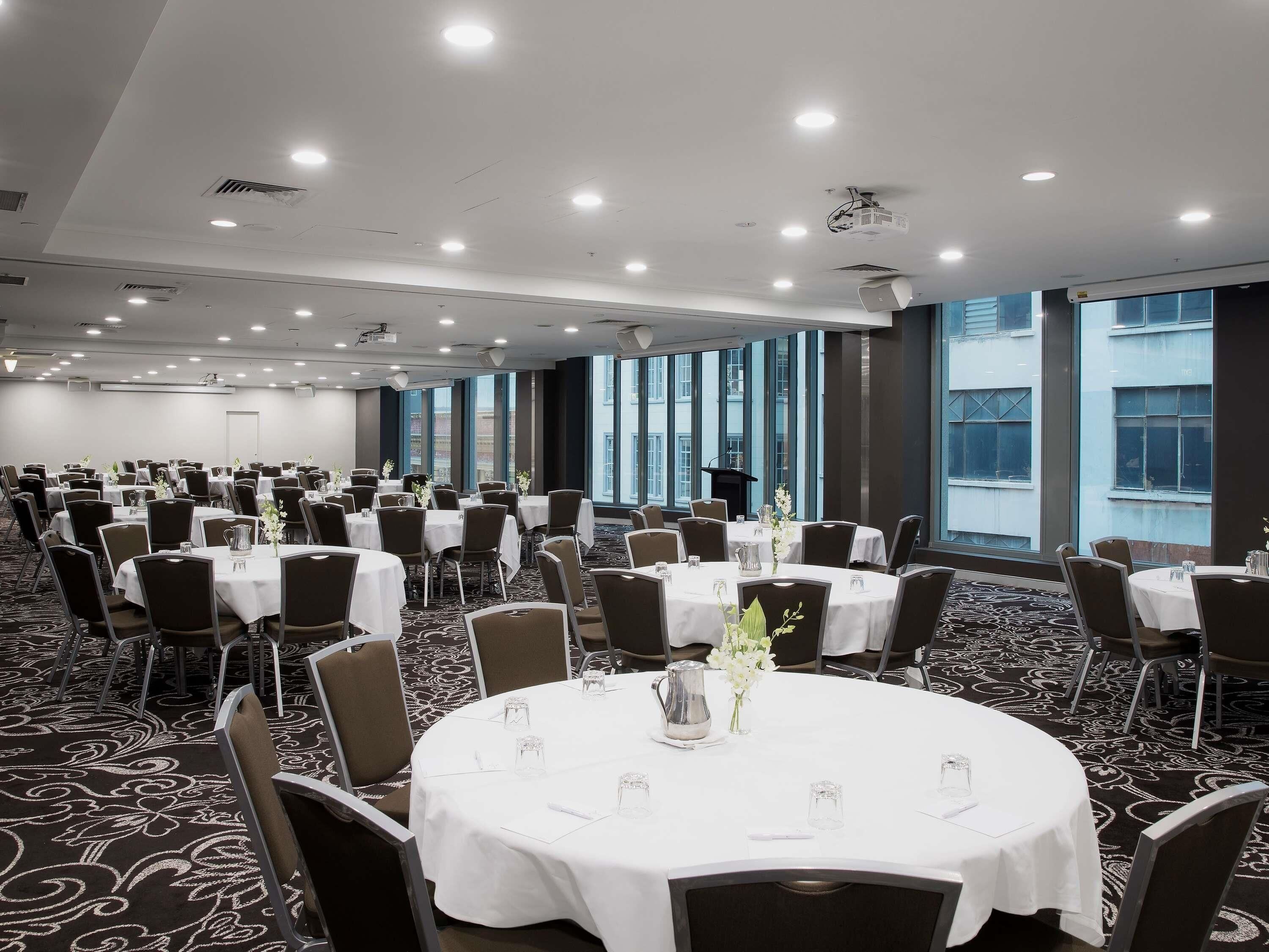 A conference room with round tables, chairs, and a carpeted floor.