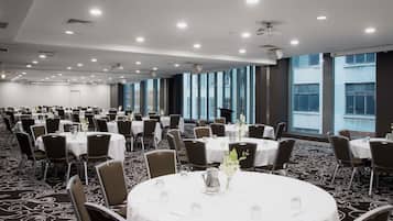 Un salón de conferencias con mesas redondas, sillas y suelo alfombrado.
