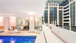 Un área moderna de piscina interior con sillas de descanso y equipo de ejercicio.