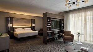 Une chambre d’hôtel moderne dotée d’un grand lit, d’une télévision, d’un coin salon et d’un lustre.