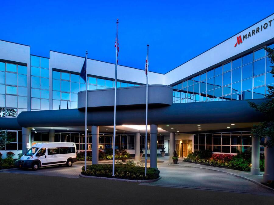 Fachada de un hotel Marriott con diseño moderno, amplias ventanas y zona de estacionamiento techada.