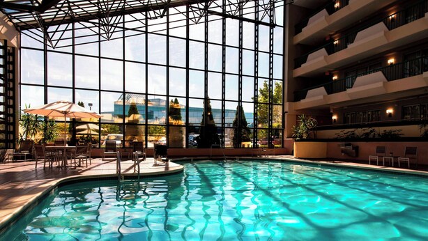Une piscine intérieure à l’eau claire, entourée d’une structure vitrée offrant une vue sur l’extérieur.