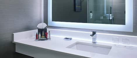 A modern bathroom with a white sink, a large mirror, and a glass shower enclosure.