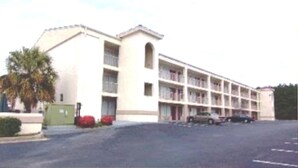 A multi-story motel with a central courtyard, featuring a parking lot and a green gate. - Deerfield Inn & Suites (Madison)