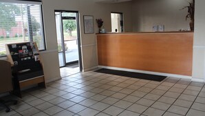 A reception area with a wooden reception desk, a map on the wall, and a small plant. - Deerfield Inn & Suites (Madison)