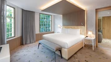 Una camera d'albergo moderna con un letto grande, una panca, un comodino e uno specchio.