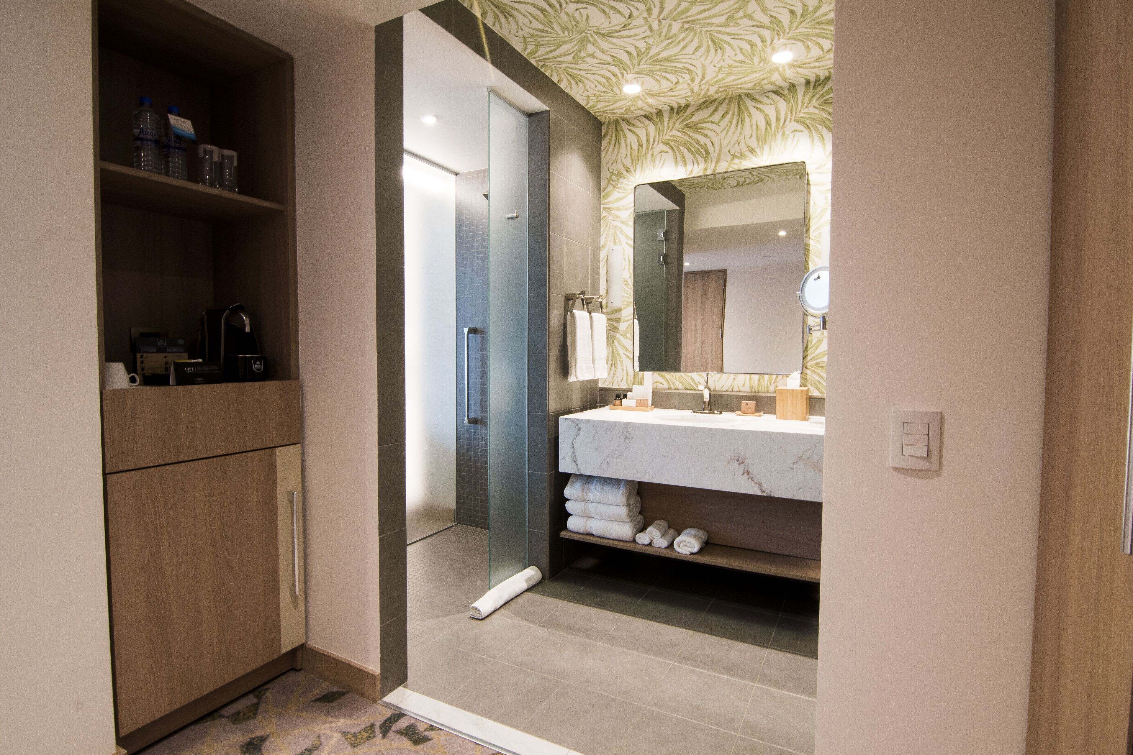 A modern bathroom with a marble sink, a large mirror, and a wooden cabinet with toiletries.