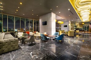 Relax in a spacious lobby with sofas, armchairs, and round tables, offering a welcoming environment.