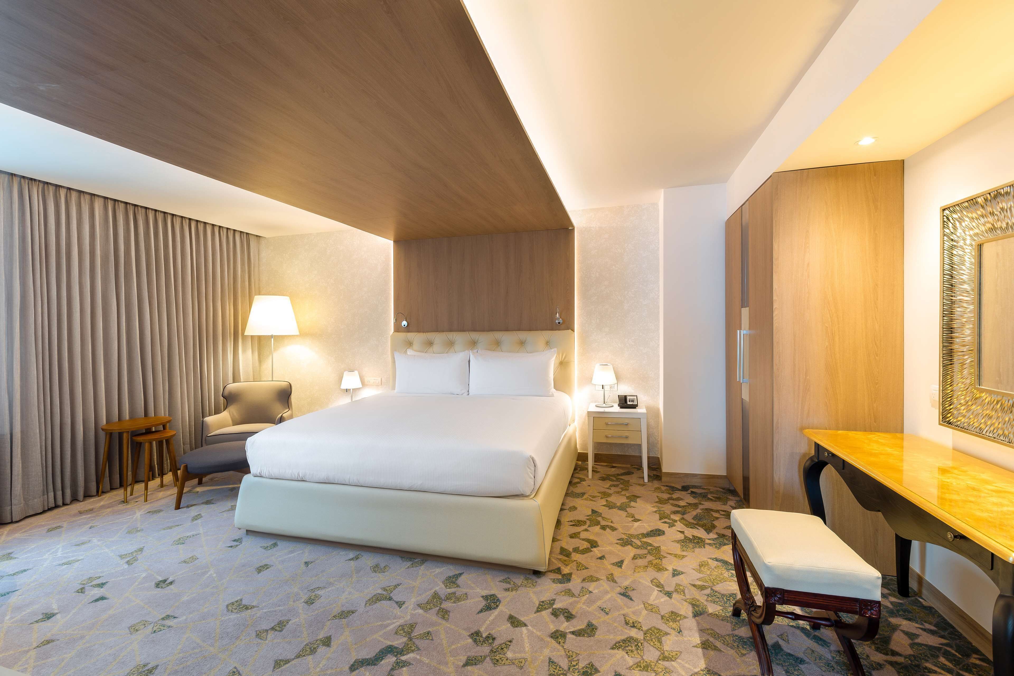 Ein modernes Hotelzimmer mit einem großen Bett, Nachttischen, einem Schreibtisch und einem Stuhl.