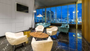 Un salon moderne avec vue sur la ville, comprenant un canapé, des fauteuils et une table basse.