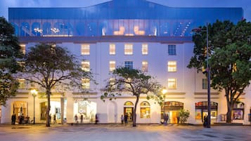 Un hotel moderno con fachada de vidrio, ventanas amplias y un patio espacioso.