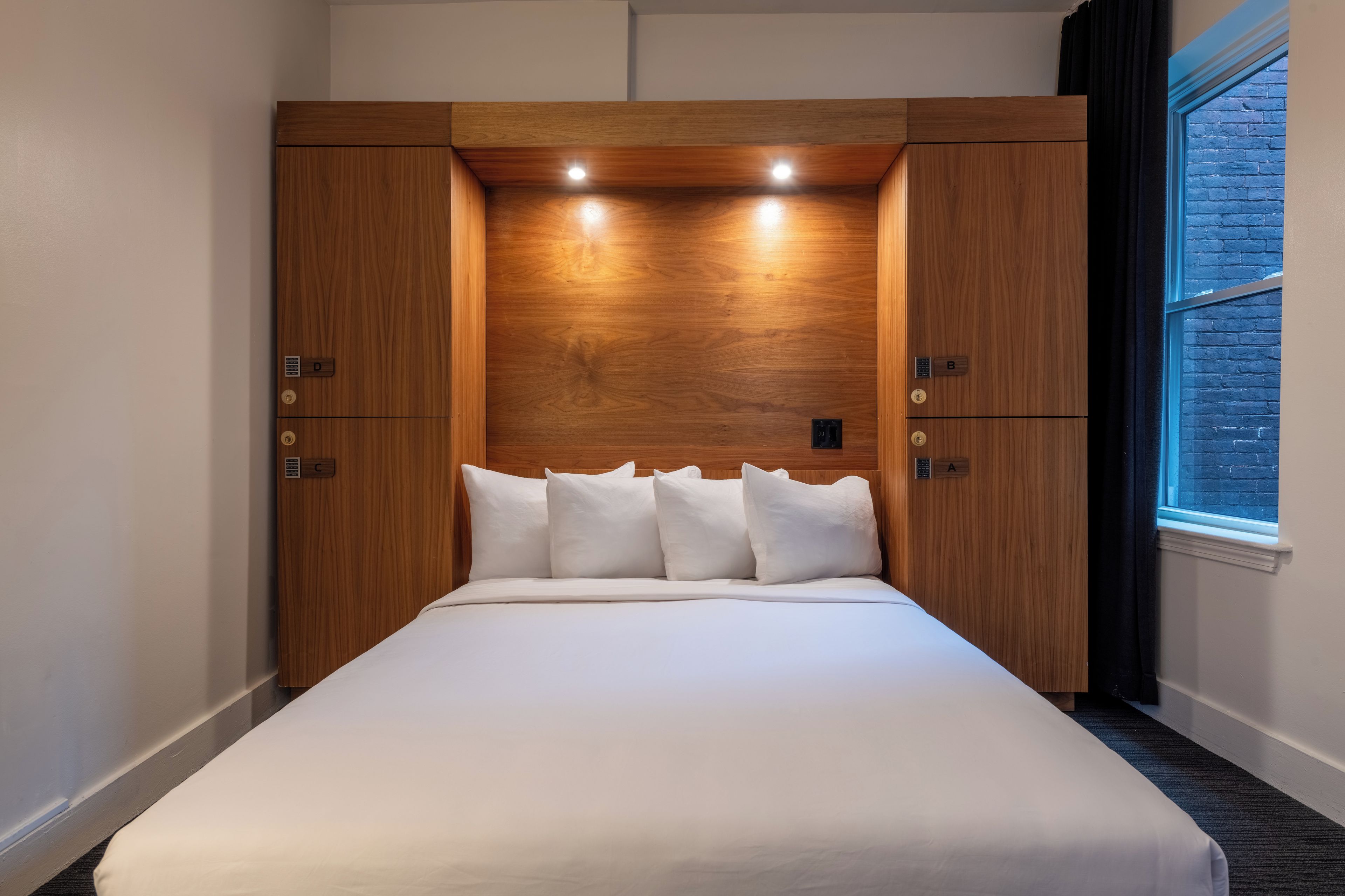 Une chambre d’hôtel avec un lit, une tête de lit en bois et une fenêtre.
