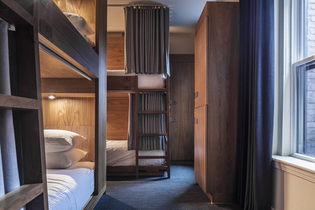A compact, multi-level room with bunk beds, a wardrobe, and a window.
