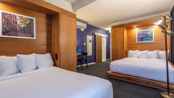 A hotel room with two beds, a desk, and a chair. There are wall-mounted air conditioning units and a lamp.