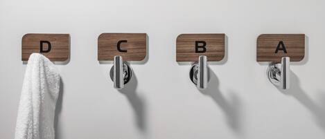 Une salle de bain avec quatre porte-serviettes étiquetés A, B, C et D, et une serviette blanche accrochée au porte-serviettes D.