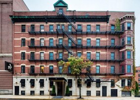 Egy többemeletes, téglából épült épület, amelyen tűzlétra található, az elején pedig egy „Hotel IVY” feliratú tábla és egy fa áll.