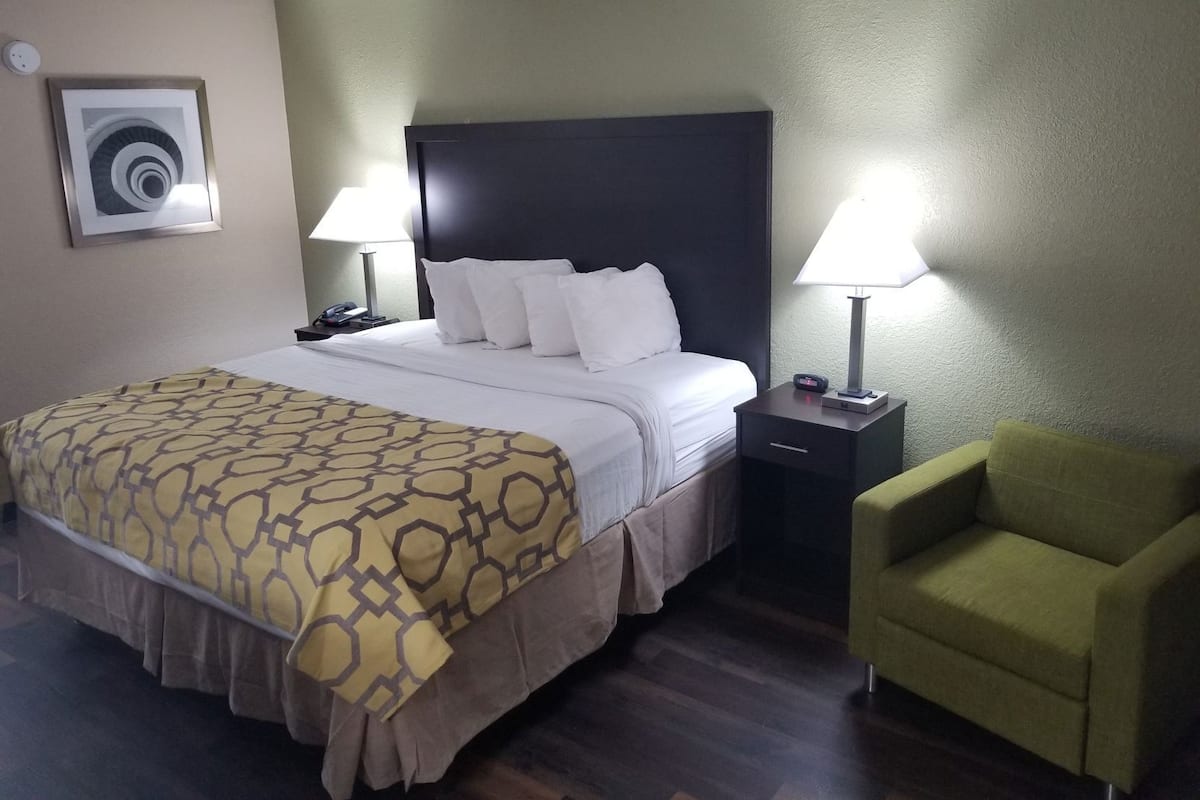 Une chambre d’hôtel comprenant un lit, deux tables de chevet, une chaise et un appareil de climatisation fixé au mur.