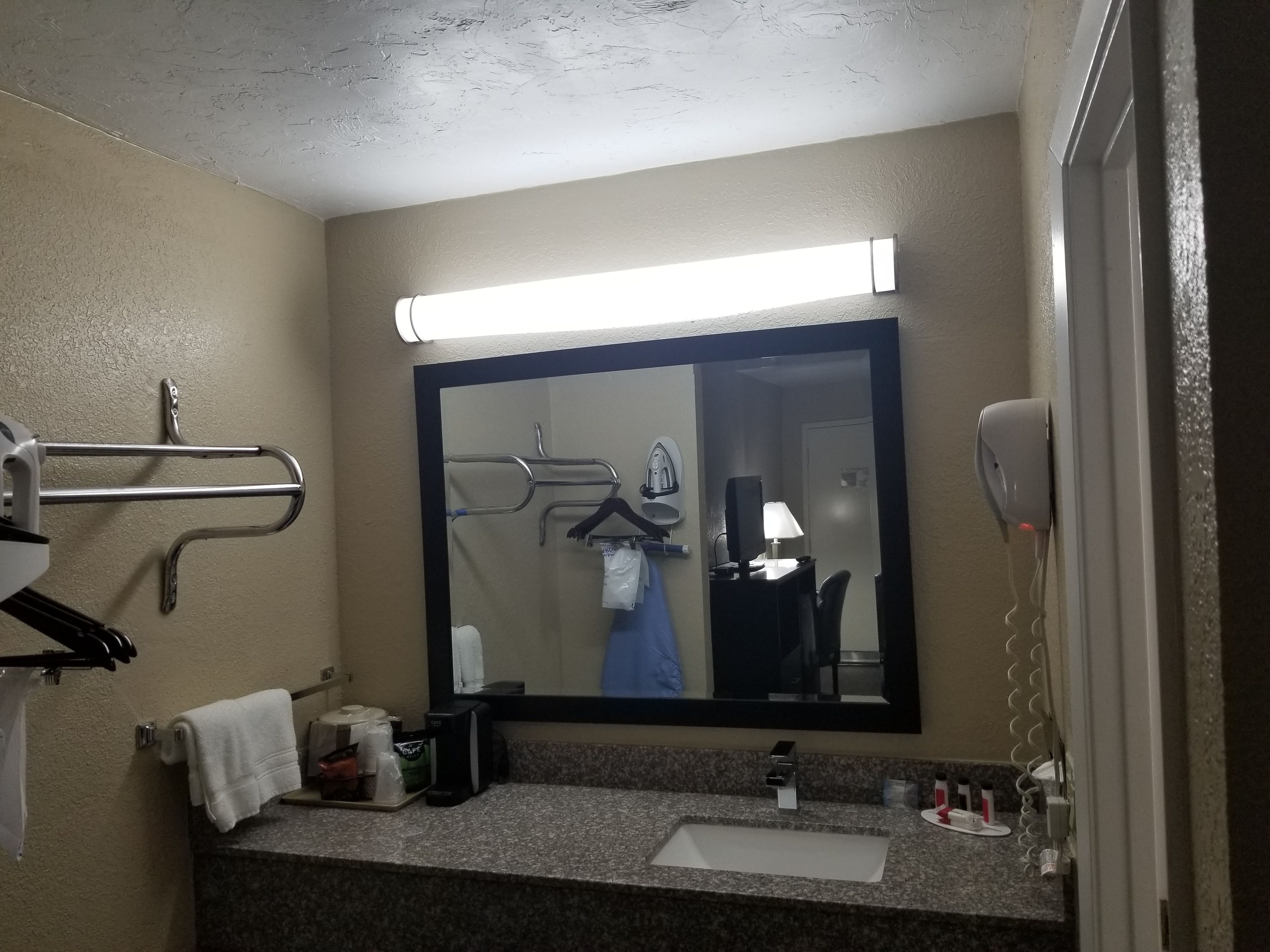 A bathroom with a sink, mirror, towel rack, and a hand dryer.