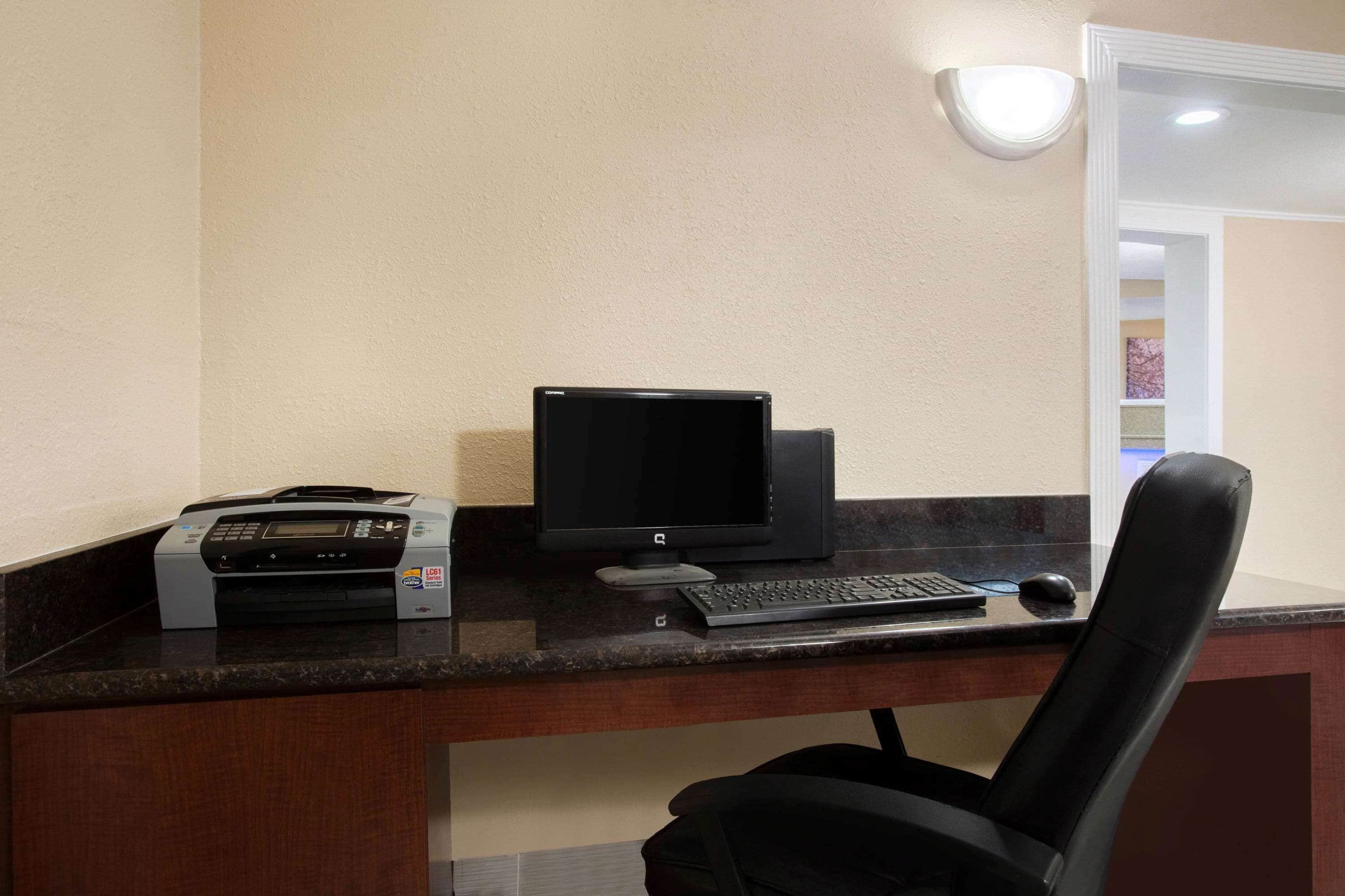 A desk with a printer, monitor, keyboard, and mouse.