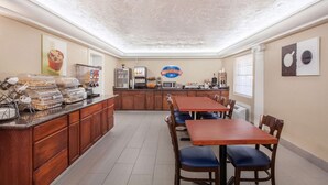A breakfast bar with a coffee machine, a microwave, and a sign reading "Breakfast Corner." There are several wooden tables and chairs arranged around the bar. - Baymont by Wyndham Lake City I-75 (Lake City)