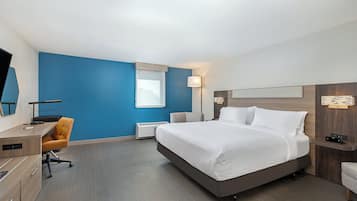 Habitación de hotel con cama, escritorio, silla y televisor.