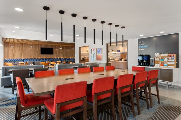 A modern hotel lobby with a large dining area, a coffee station, and a TV mounted on the wall. - Holiday Inn Express Atlanta Airport - North by IHG (College Park)