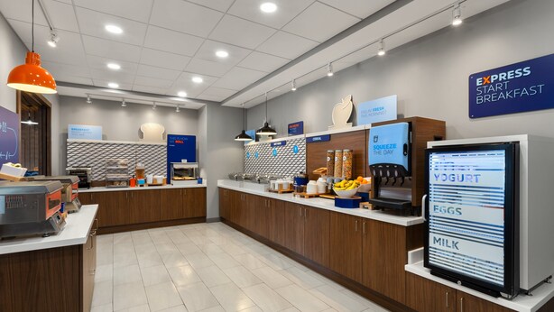A modern breakfast area with a digital menu display, wooden cabinets, and a sign indicating 'Express Start Breakfast'.
