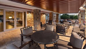 An outdoor patio area with stone pillars, a round table, and chairs.