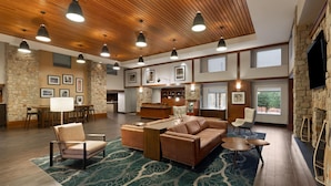 A spacious living area with a wooden ceiling, stone walls, a large sofa, a coffee table, and a fireplace.