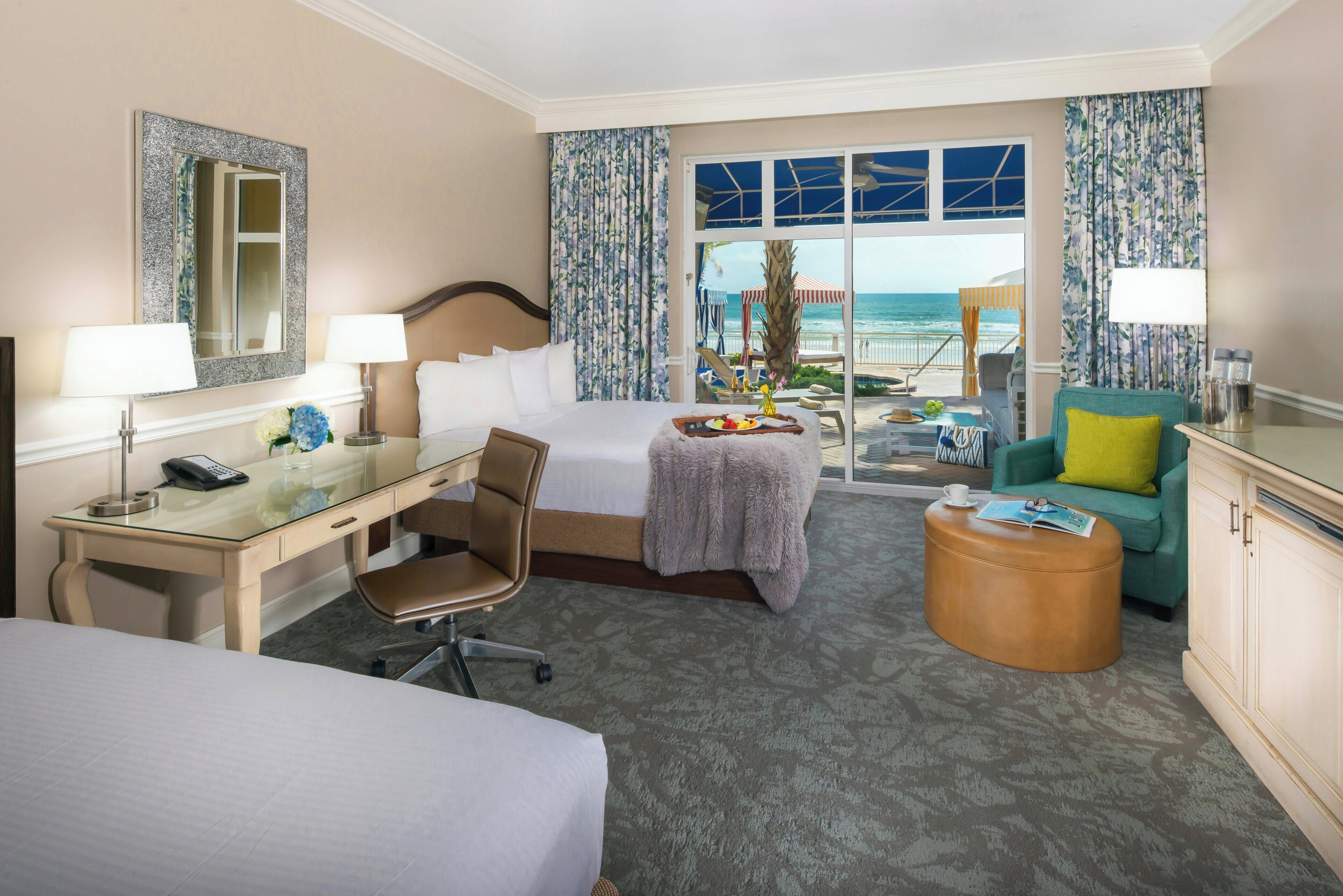 Una habitación de hotel con cama, escritorio, silla y vista a la playa.